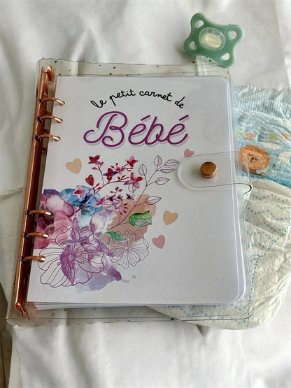 Le petit carnet de bébé rose, version biberon ou allaitement, tenu dans la main