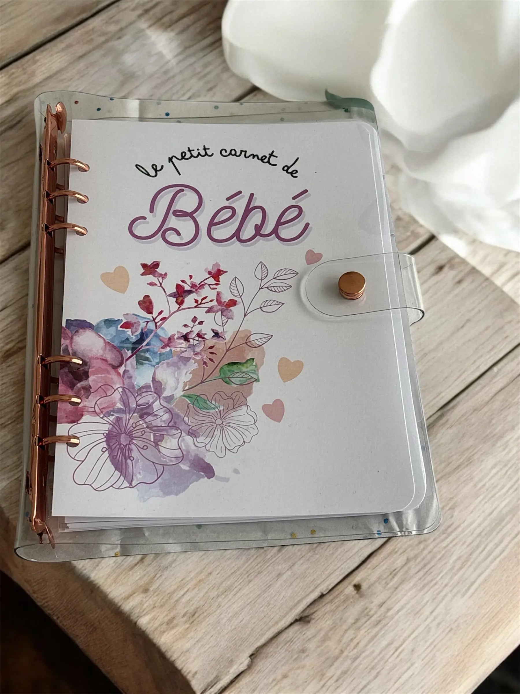 Le petit carnet de bébé rose, version biberon ou allaitement, tenu dans la main