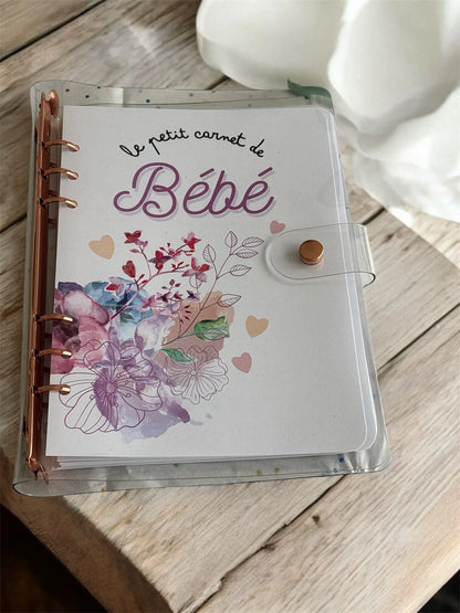 Le petit carnet de bébé rose, version biberon ou allaitement, tenu dans la main